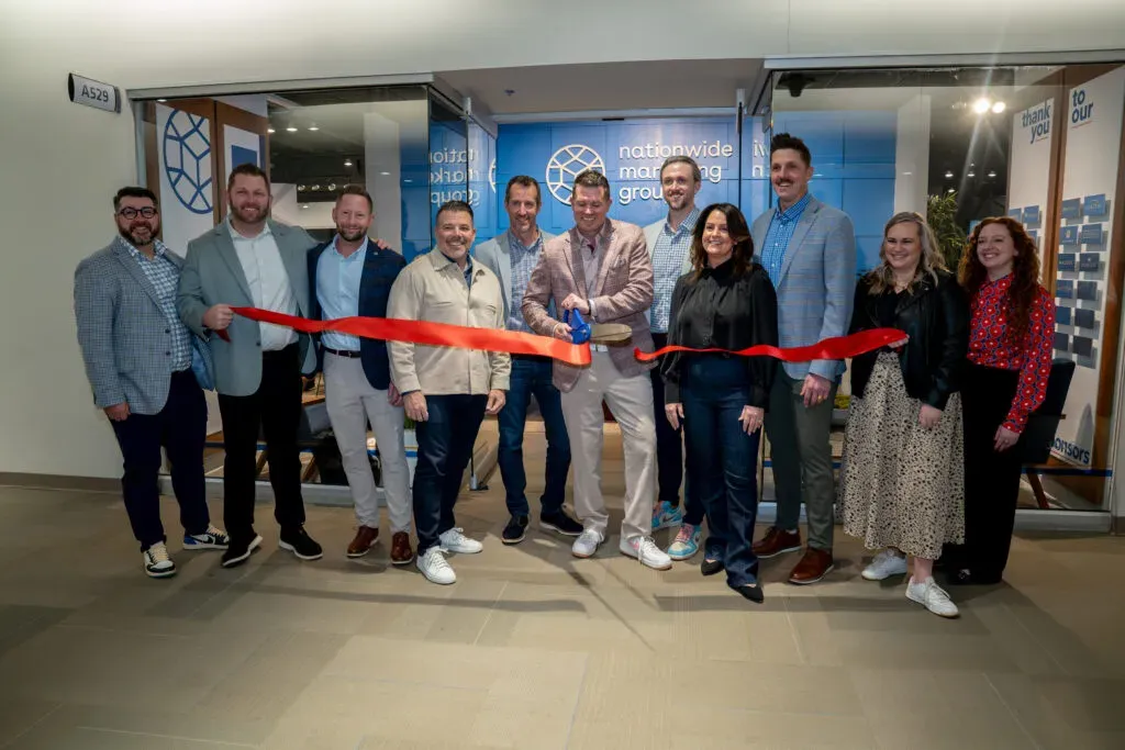 Small group of people lined up to do a ribbon cutting in front of a showroom